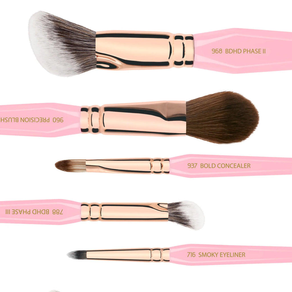 Set of makeup brushes with pink handles and rose gold ferrules on a white background.