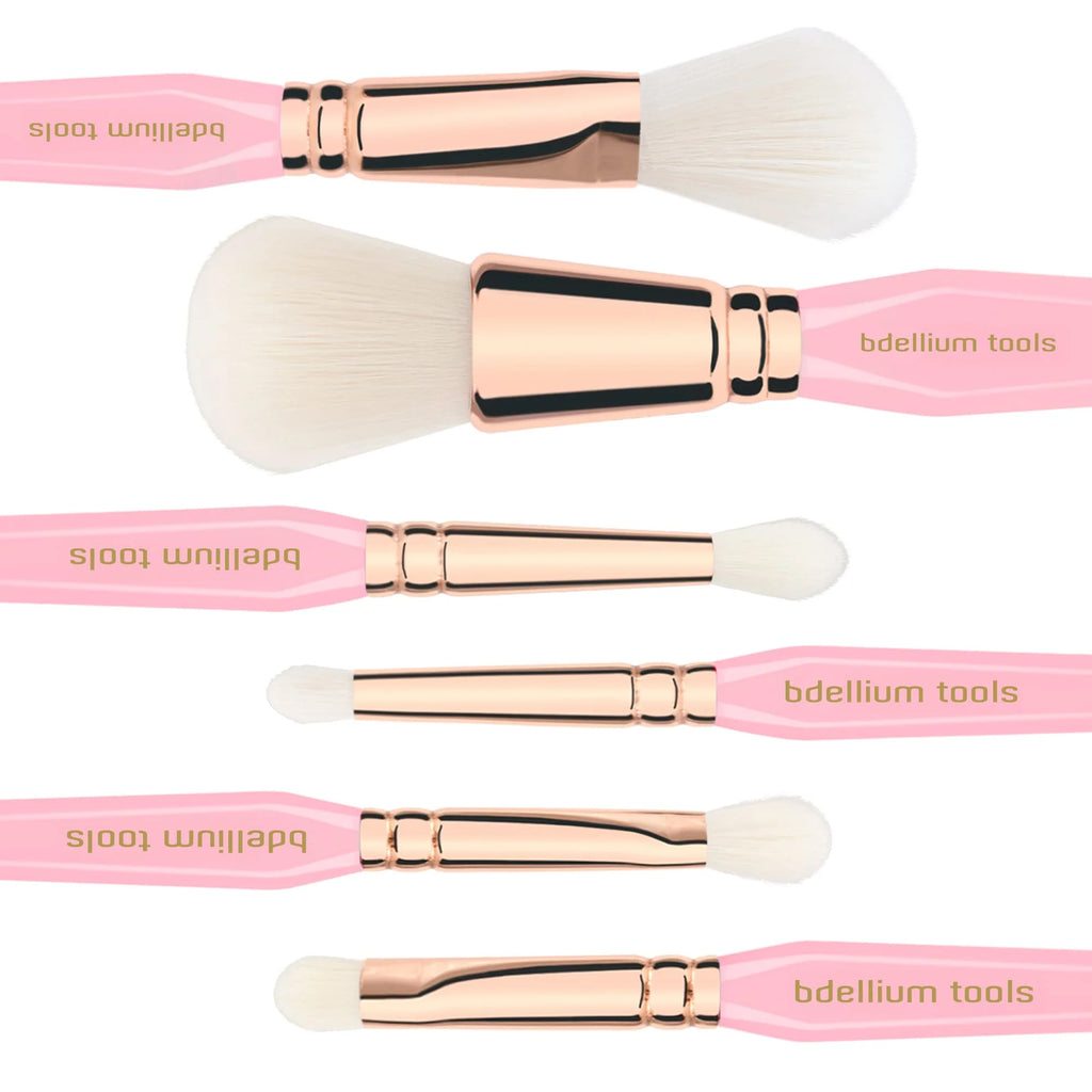 Set of makeup brushes with pink handles and rose gold ferrules on a white background.