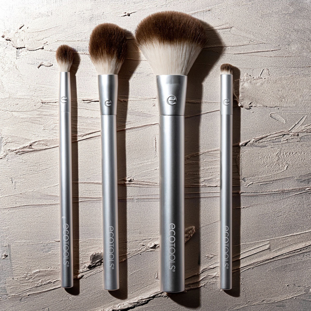 Set of makeup brushes with silver handles on a textured gray background