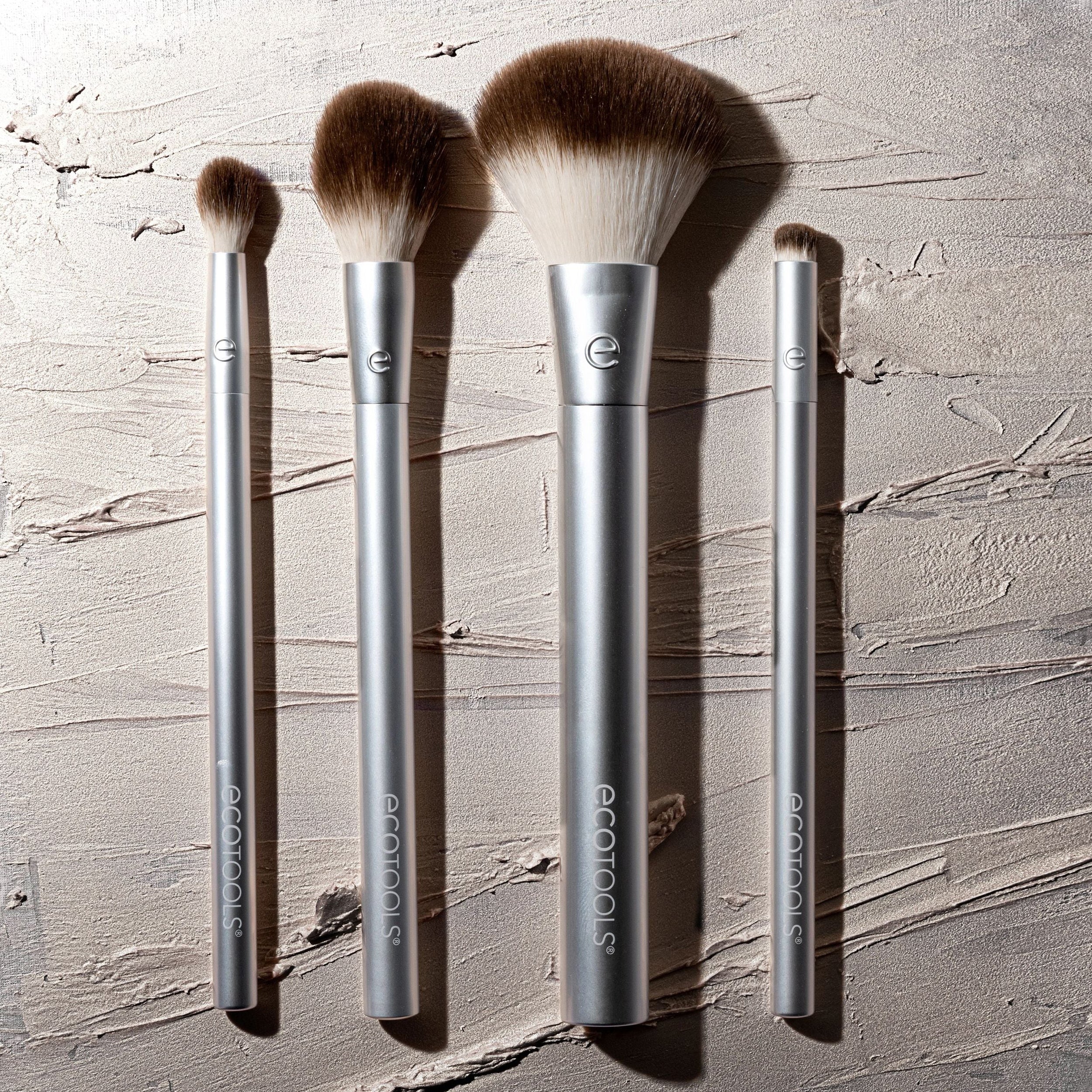 Set of makeup brushes with silver handles on a textured gray background