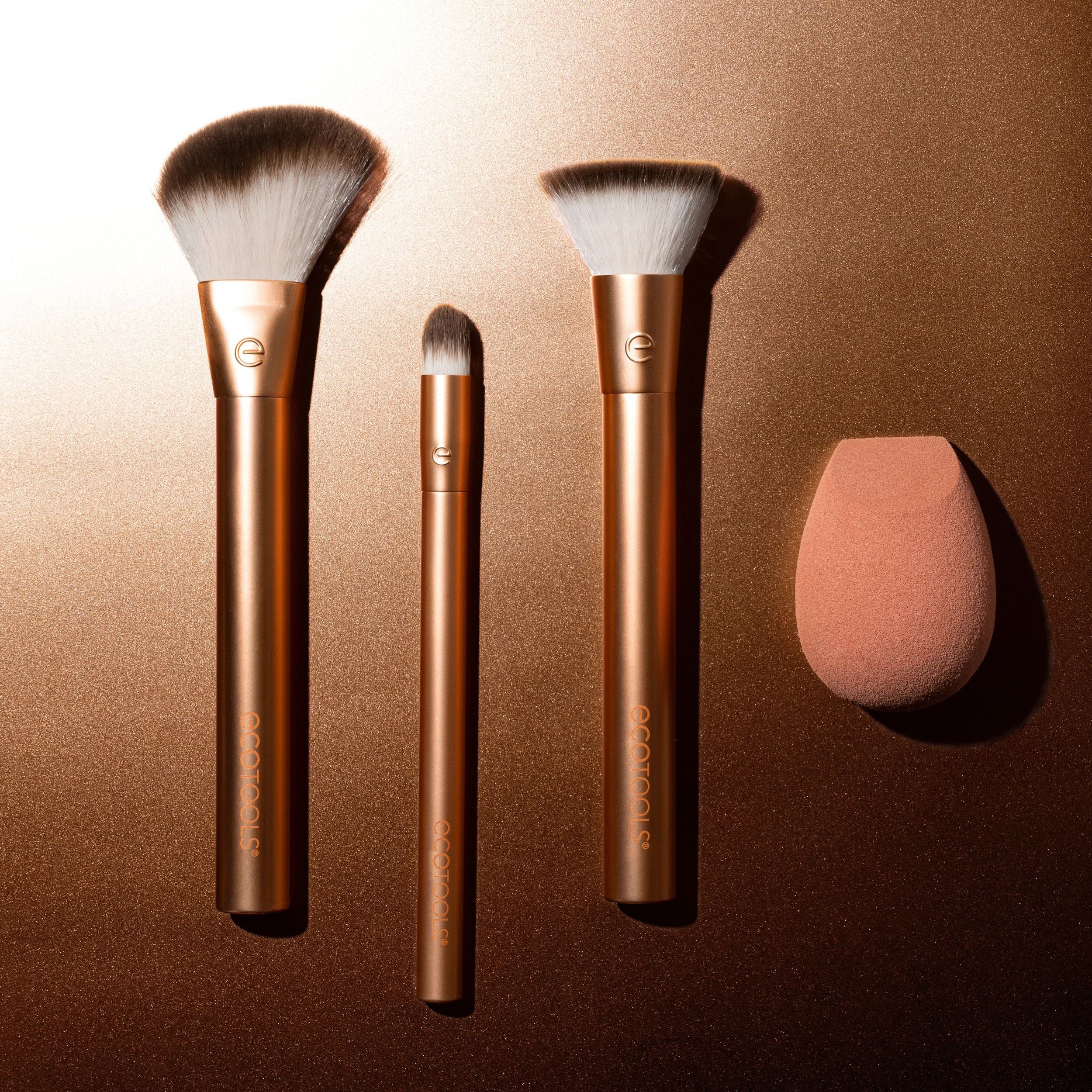 Set of makeup brushes and a sponge on a bronze background