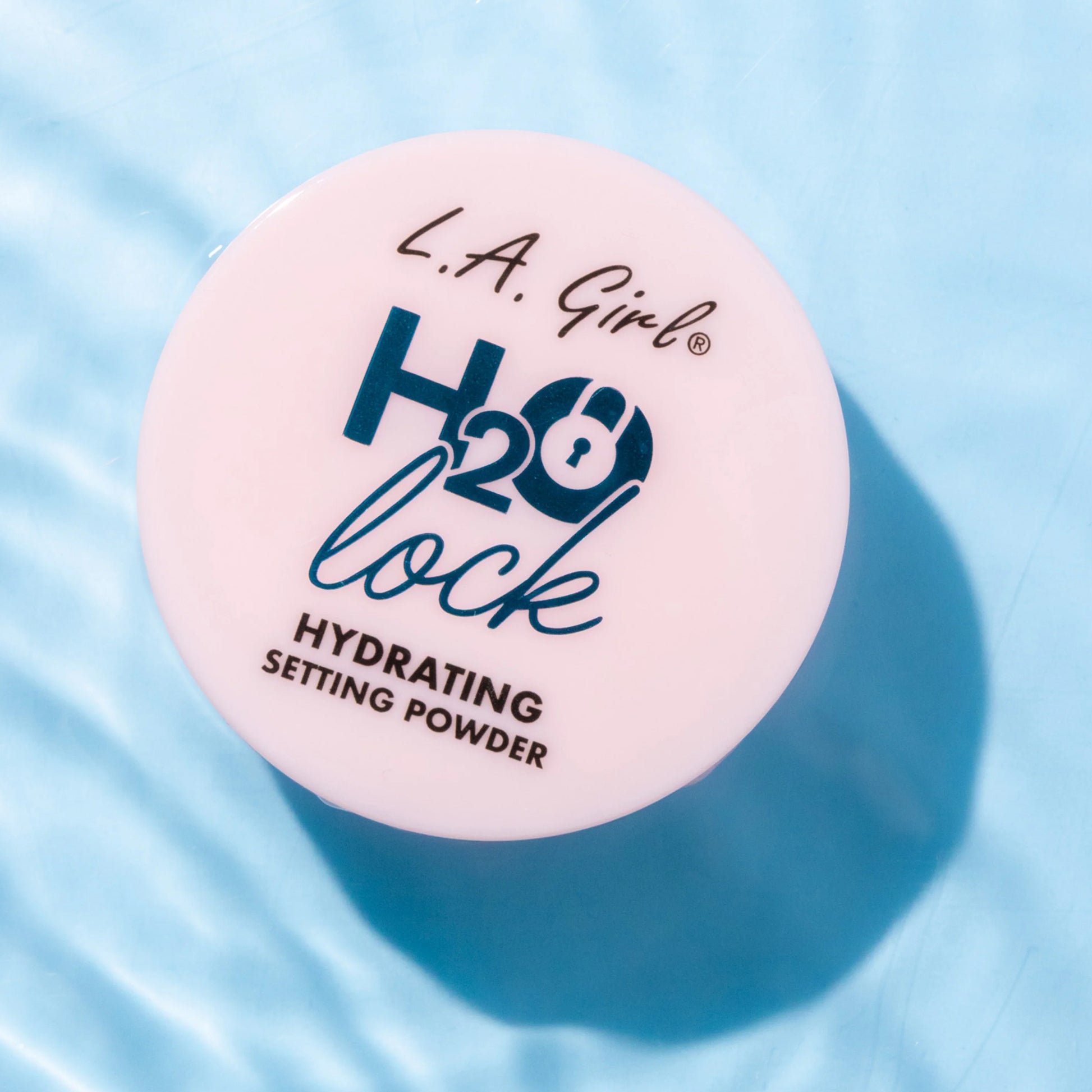 L.A. Girl H2O Lock hydrating setting powder container on a blue fabric background