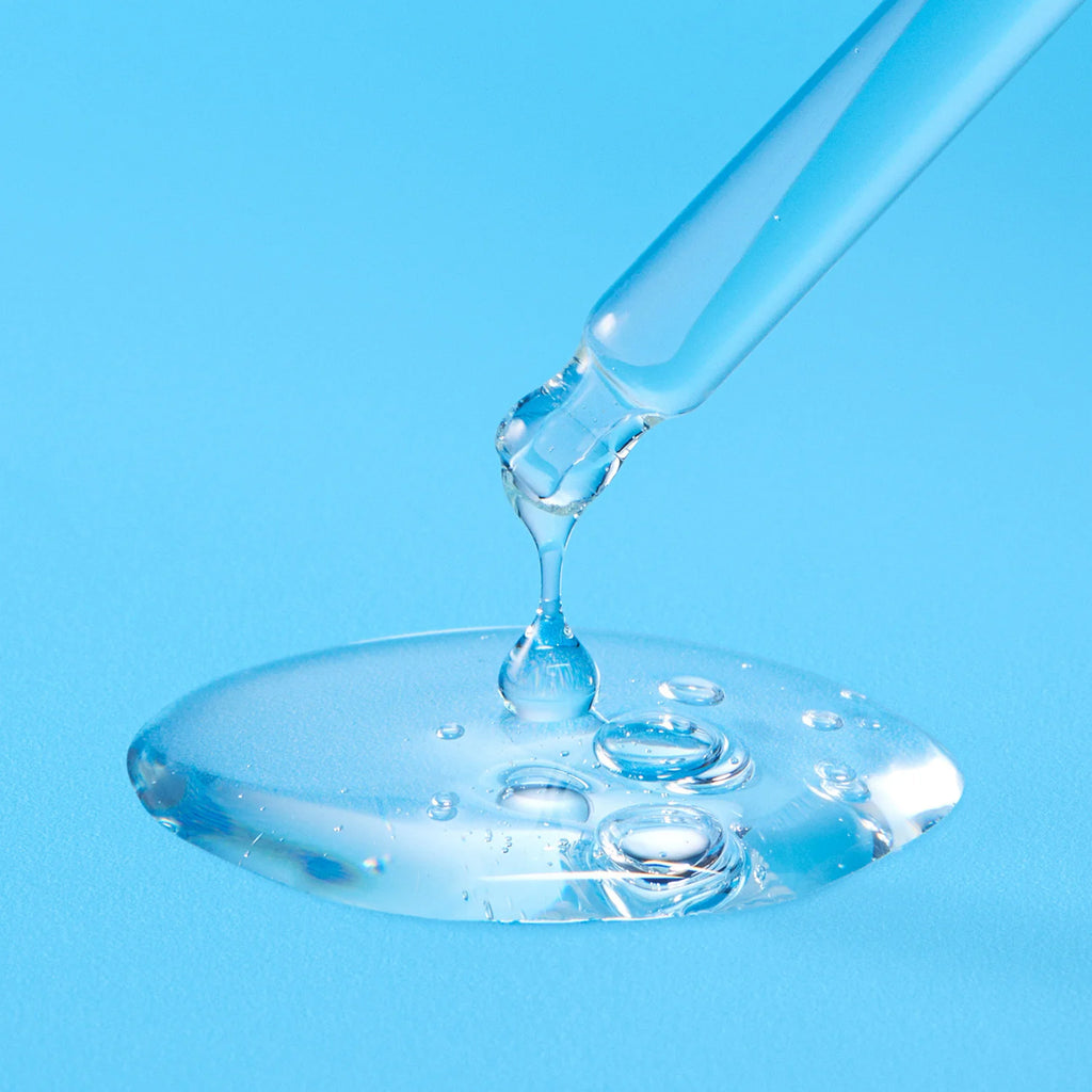 Glass dropper with liquid on a blue background